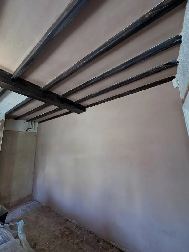 A wall in Laindon plastered smooth beneath a dark beamed ceiling