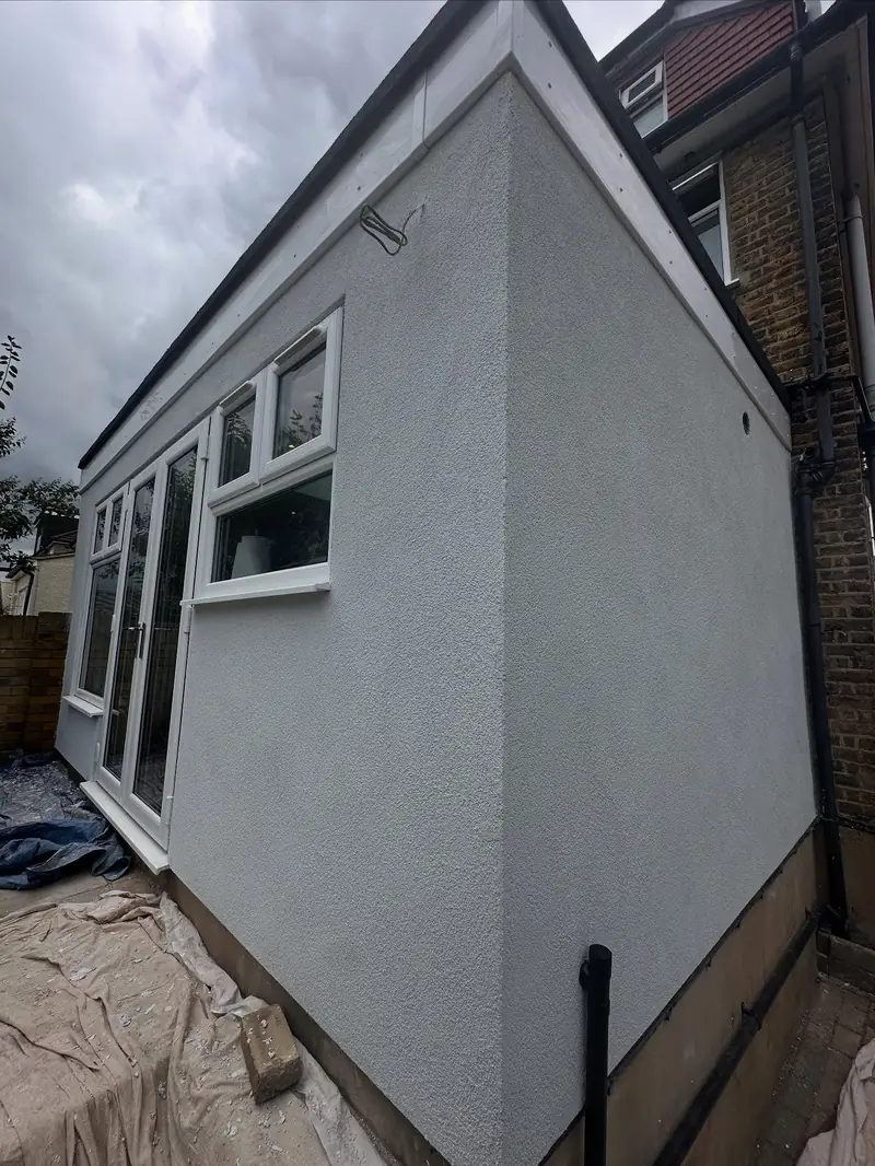 The same extension wall rendered smooth and finished in pale grey