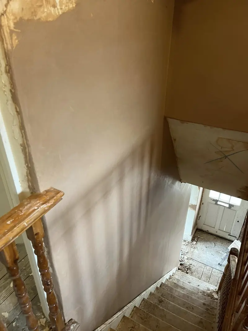 The same stairwell wall re-plastered smooth above the banister