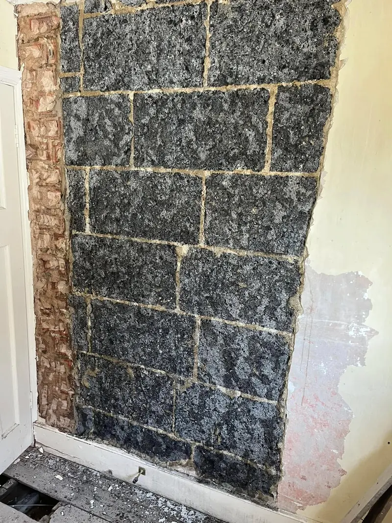 A stairwell wall stripped back to bare blockwork before plastering